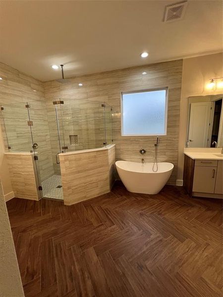 Bathroom featuring separate shower and tub, vanity, and parquet flooring