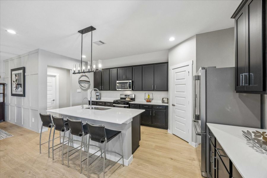 Now we will take a closer look at the gorgeous kitchen!  Quartz countertops, island with large sink with designer kitchen faucet, upgraded chrome cabinet and drawer hardware.  The kitchen sink has a reverse osmosis drinking water system.