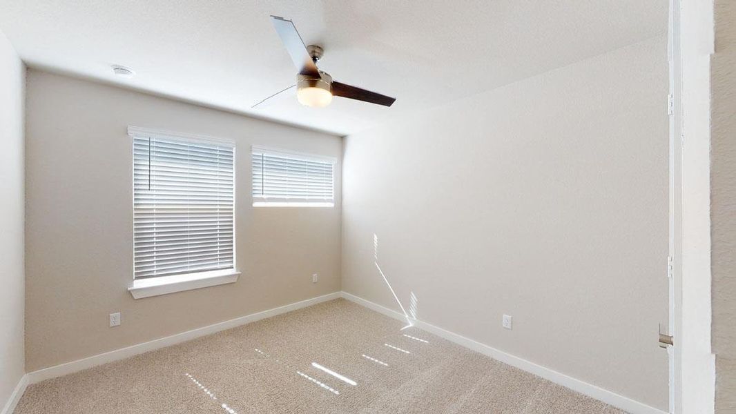 A well-lit bedroom features plush carpet and an efficient ceiling fan for optimal comfort. A well-lit bedroom features plush carpet and an efficient ceiling fan for optimal comfort.