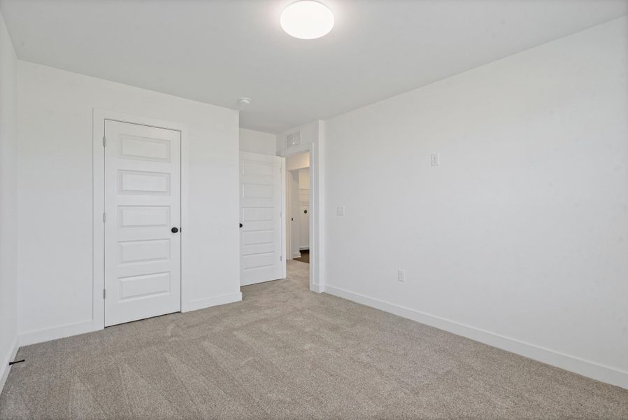 Neutral-toned carpet flooring, white walls, and a flush mount ceiling light Neutral-toned carpet flooring, white walls, and a flush mount ceiling light