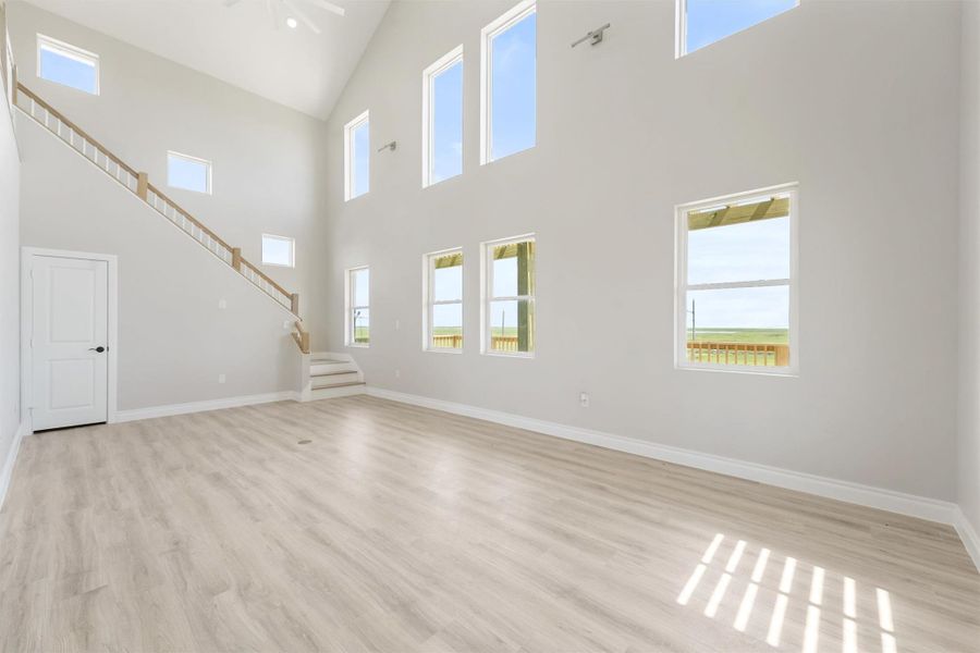 This spacious, light-filled living room features high ceilings, multiple large windows, and light wood flooring, creating an open and airy atmosphere. A modern staircase leads to the upper level, adding to the room's contemporary style. This spacious, light-filled living room features high ceilings, multiple large windows, and light wood flooring, creating an open and airy atmosphere. A modern staircase leads to the upper level, adding to the room's contemporary style.