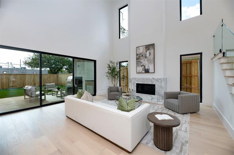 Living area featuring wood finished floors, a high end fireplace, and a towering ceiling Living area featuring wood finished floors, a high end fireplace, and a towering ceiling