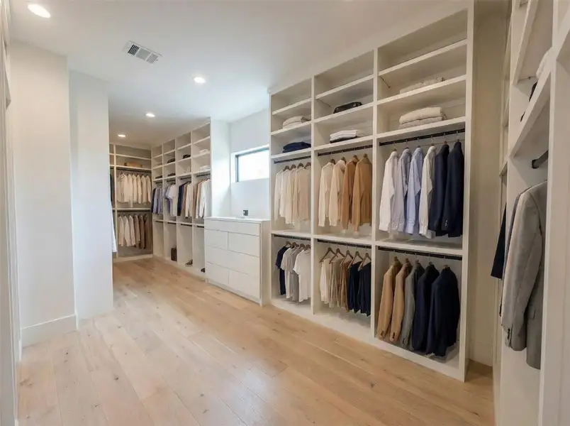 Primary Closet- Custom wall-to-wall cabinetry, double-hang sections, open cubbies, engineered white oak floors — a true dressing room. (Rendering)