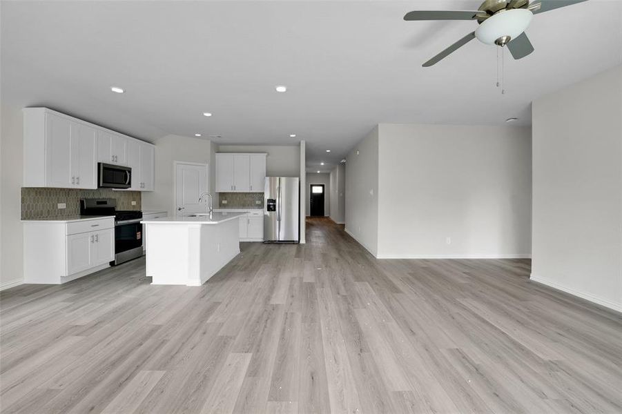 Kitchen with open floor plan, backsplash, appliances with stainless steel finishes, an island with sink, and recessed lighting Kitchen with open floor plan, backsplash, appliances with stainless steel finishes, an island with sink, and recessed lighting