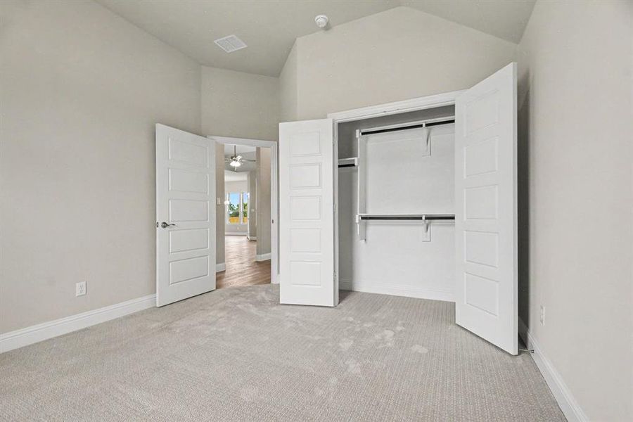 Bedroom featuring vaulted ceilings, light gray wall paint, white trim, and light gray carpet flooring Bedroom featuring vaulted ceilings, light gray wall paint, white trim, and light gray carpet flooring