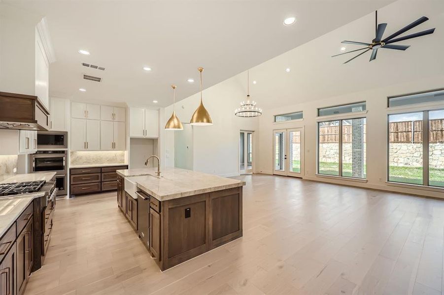 Kitchen featuring appliances with stainless steel finishes, sink, a spacious island, white cabinetry, and pendant lighting