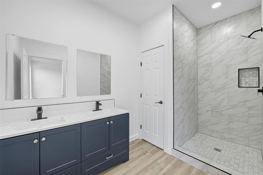 Bathroom with a shower stall, double vanity, light wood-style flooring, and recessed lighting Bathroom with a shower stall, double vanity, light wood-style flooring, and recessed lighting