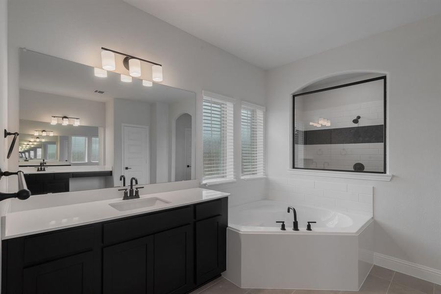 Primary Bathroom with tile patterned flooring, independent shower and bath, and vanity