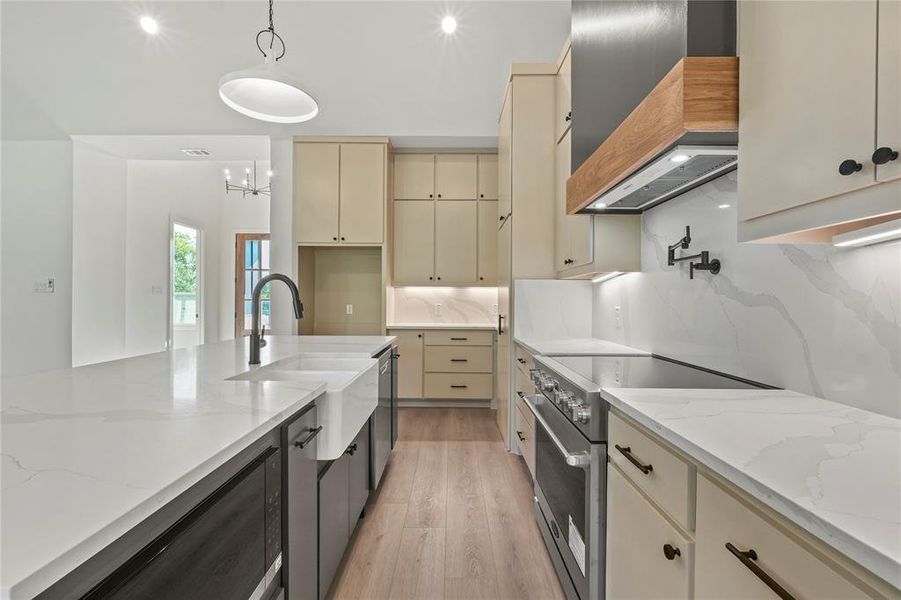 Kitchen with cream cabinets, light stone counters, high end stove, pendant lighting, and recessed lighting Kitchen with cream cabinets, light stone counters, high end stove, pendant lighting, and recessed lighting