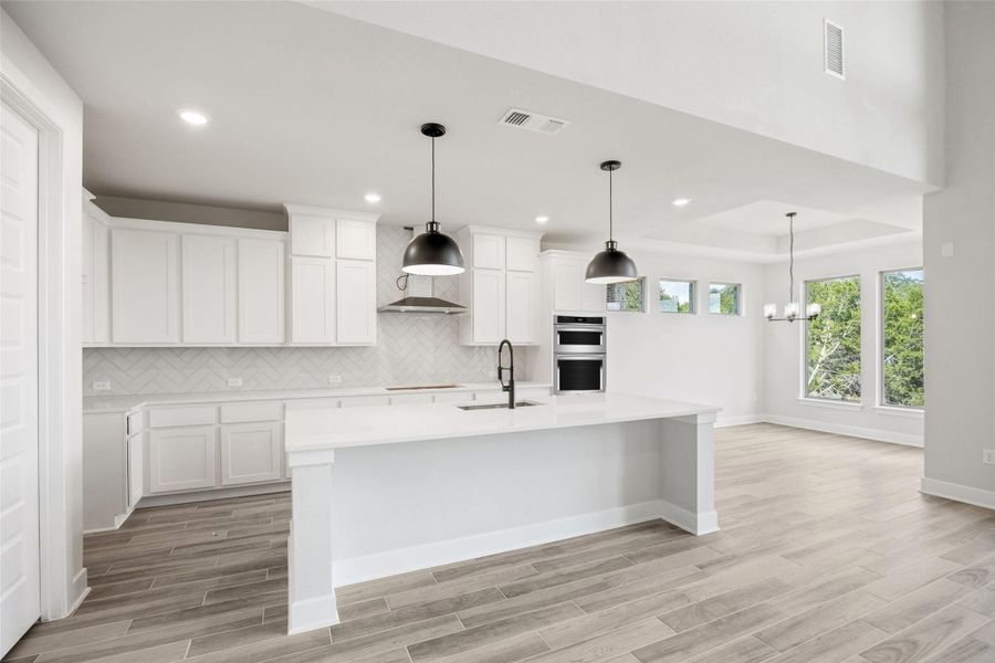 Kitchen with decorative backsplash, decorative light fixtures, white cabinets, and recessed lighting Kitchen with decorative backsplash, decorative light fixtures, white cabinets, and recessed lighting