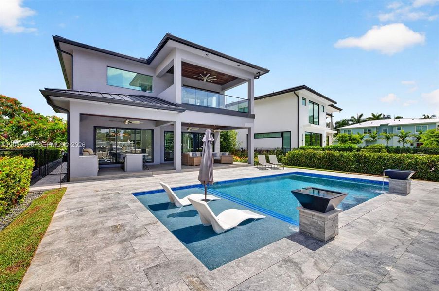 Salt chlorinated pool w/ water features, LED color changing light, sun shelf with umbrella hole and in water stools. Stone decking surrounds the pool