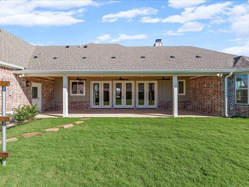 Rear view of property with board and batten siding, a ceiling fan, and roof with shingles