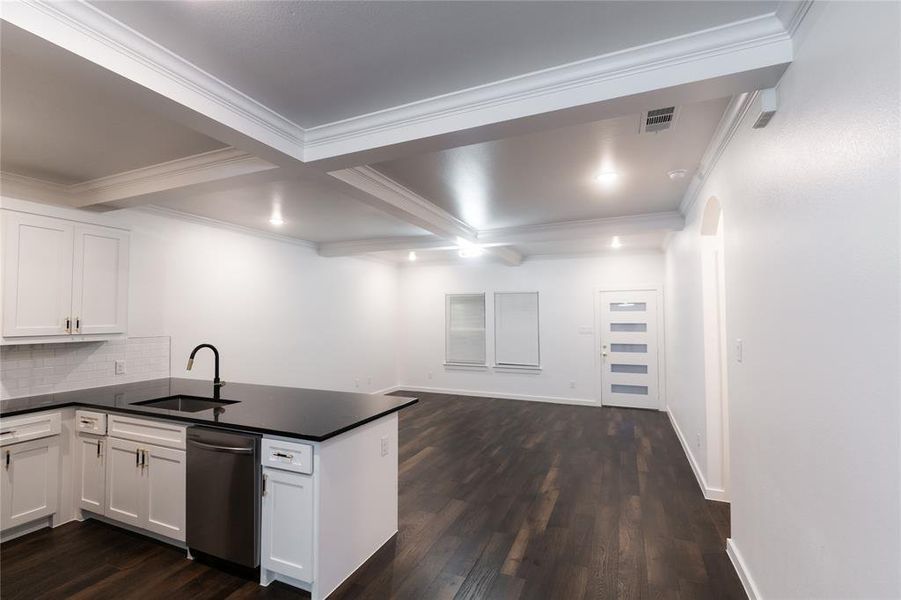 Kitchen with dark countertops, dishwasher, a sink, visible vents, and a peninsula Kitchen with dark countertops, dishwasher, a sink, visible vents, and a peninsula