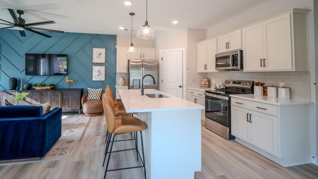 Kitchen with tile backsplash, quartz countertops, and pendant lighting with access to living area