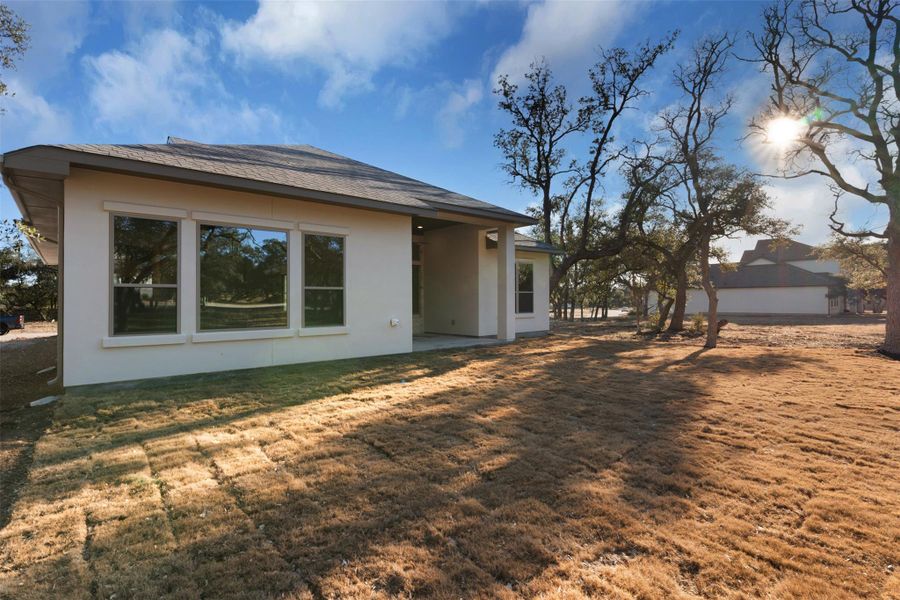 Rear view of property featuring a patio area, a yard, and stucco siding