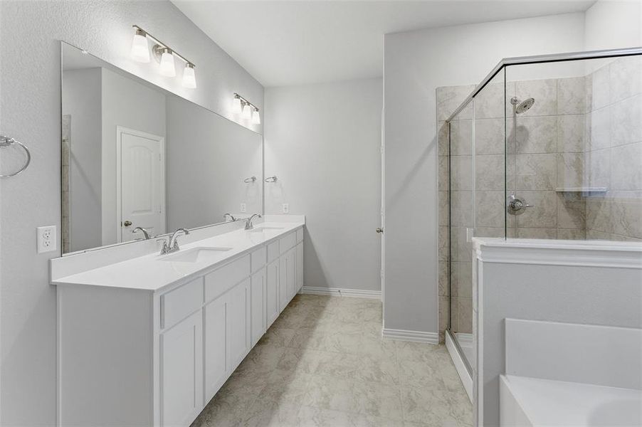Spacious bathroom featuring a dual vanity with white cabinetry and countertops, a large frameless mirror, and overhead vanity lighting Spacious bathroom featuring a dual vanity with white cabinetry and countertops, a large frameless mirror, and overhead vanity lighting