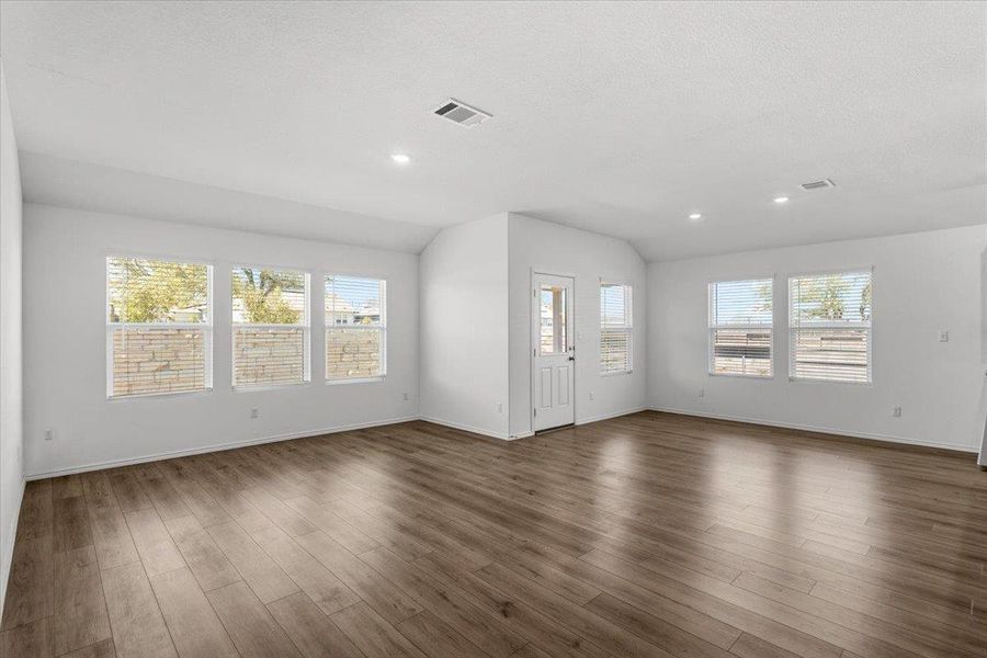 Unfurnished living room featuring lofted ceiling, dark wood-type flooring, and recessed lighting
