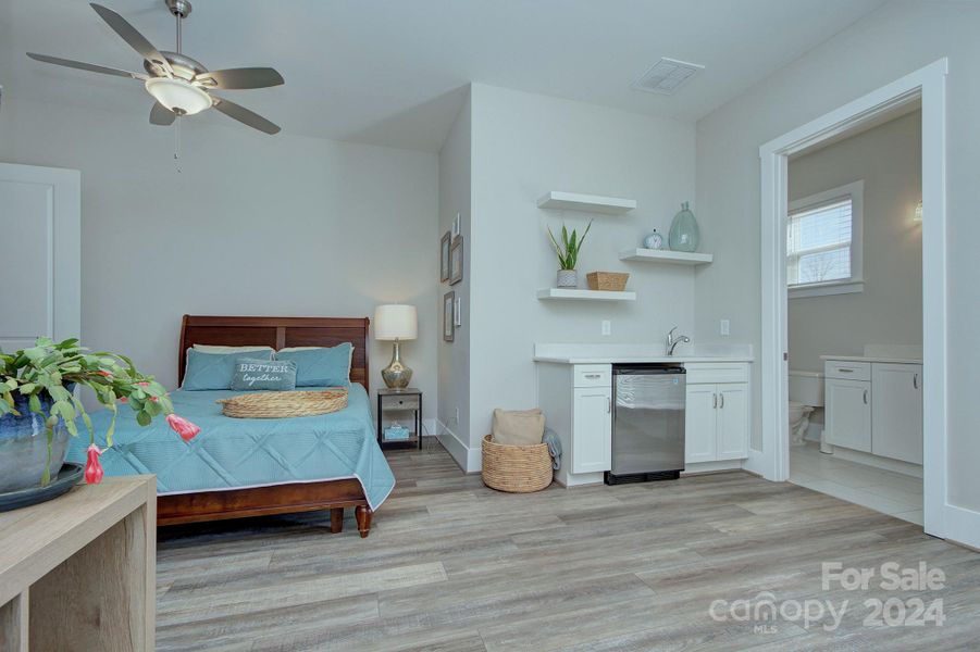 Second primary bedroom/In Law bedroom on first floor- cabinetry and room for a mini-fridge along with a sink and floating shelving