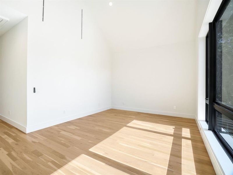 Spare room featuring light wood finished floors and lofted ceiling