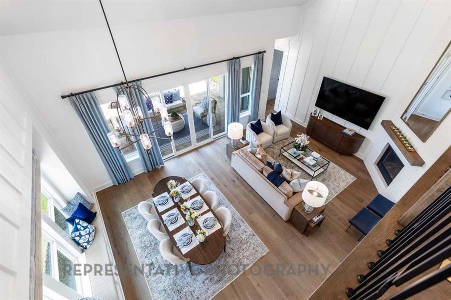 Living room featuring a glass covered fireplace, wood finished floors, and a chandelier Living room featuring a glass covered fireplace, wood finished floors, and a chandelier