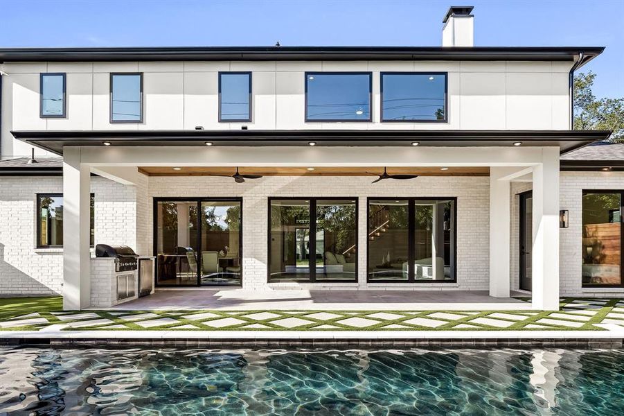 Back of property with ceiling fan, a patio area, an outdoor pool, brick siding, and area for grilling Back of property with ceiling fan, a patio area, an outdoor pool, brick siding, and area for grilling