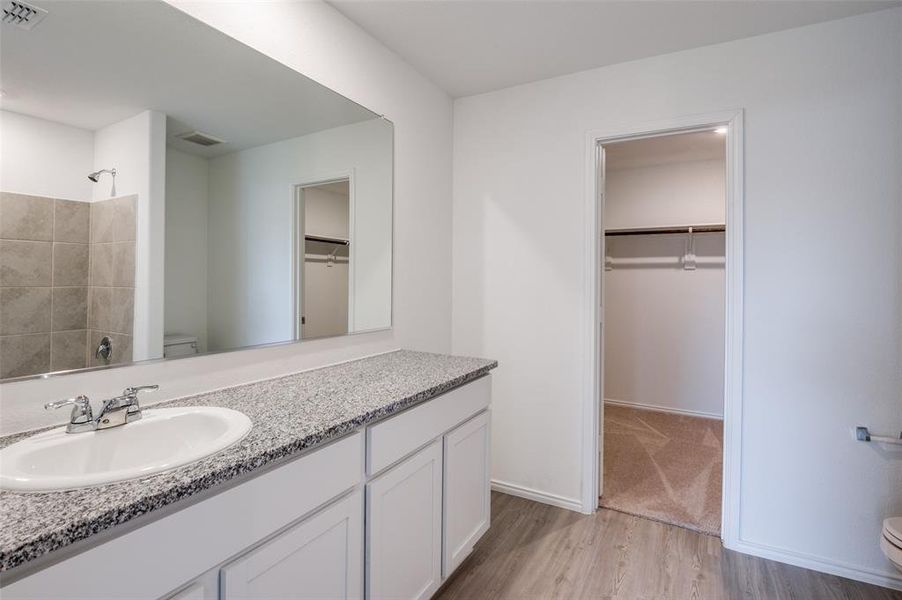 Bathroom featuring hardwood / wood-style floors, vanity, toilet, and a shower