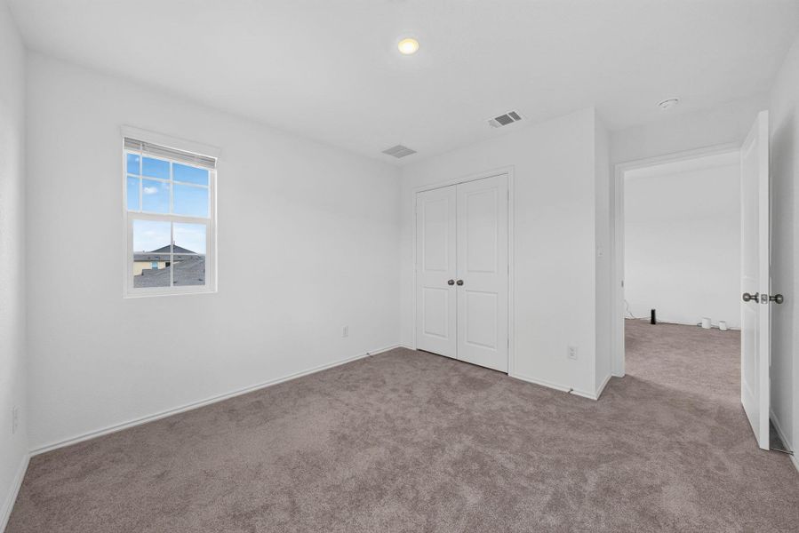 A well-lit bedroom features plush carpeting and a convenient bi-fold closet, offering comfort and practicality. A well-lit bedroom features plush carpeting and a convenient bi-fold closet, offering comfort and practicality.