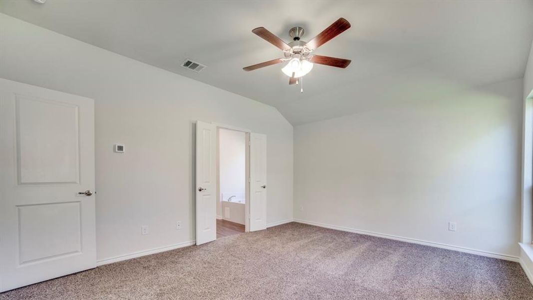 Unfurnished bedroom with ensuite bathroom, carpet floors, lofted ceiling, and ceiling fan