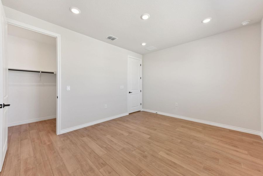 Unfurnished bedroom with recessed lighting, a walk in closet, and light wood-style floors