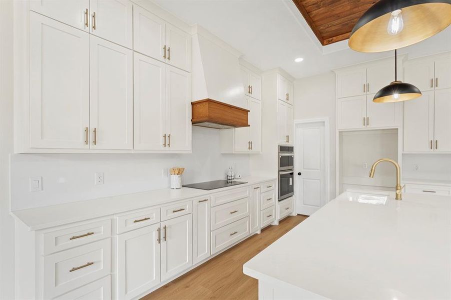 Kitchen featuring white cabinetry, pendant lighting, light wood-style floors, recessed lighting, and light stone countertops