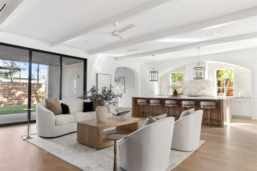 Living room with light wood-style flooring, beam ceiling, arched walkways, and ceiling fan Living room with light wood-style flooring, beam ceiling, arched walkways, and ceiling fan