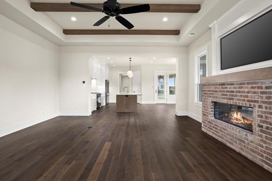 Unfurnished living room featuring a fireplace, dark hardwood / wood-style flooring, sink, and ceiling fan