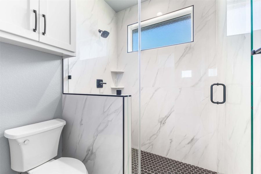 Bathroom featuring a marble finish shower and toilet Bathroom featuring a marble finish shower and toilet