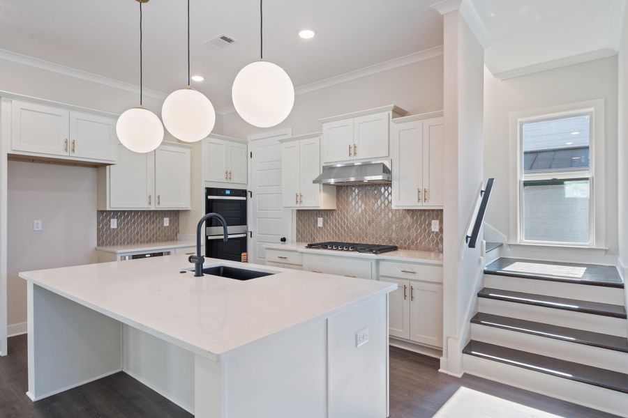 Kitchen featuring white cabinets, light quartz counters, a center island with sink, pendant lighting, and tasteful backsplash Kitchen featuring white cabinets, light quartz counters, a center island with sink, pendant lighting, and tasteful backsplash