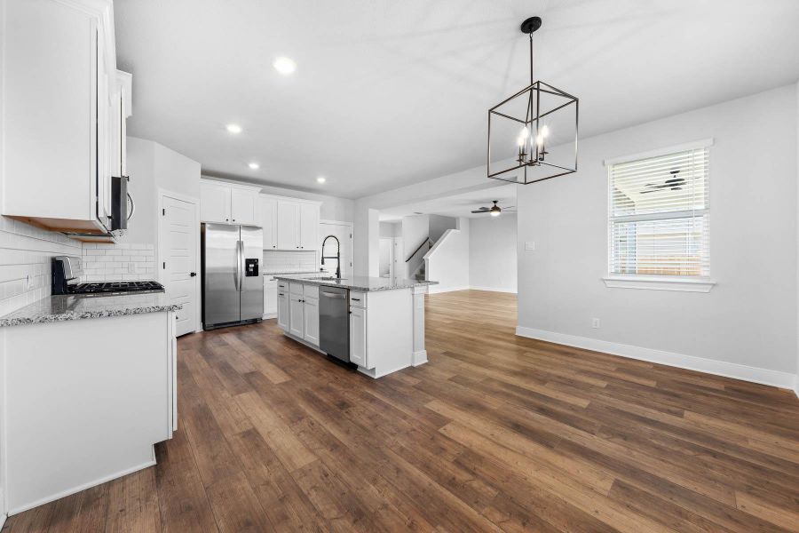 A well-appointed kitchen island anchors this open-concept living space, featuring rich hardwood flooring and a stylish overhead light fixture. A well-appointed kitchen island anchors this open-concept living space, featuring rich hardwood flooring and a stylish overhead light fixture.