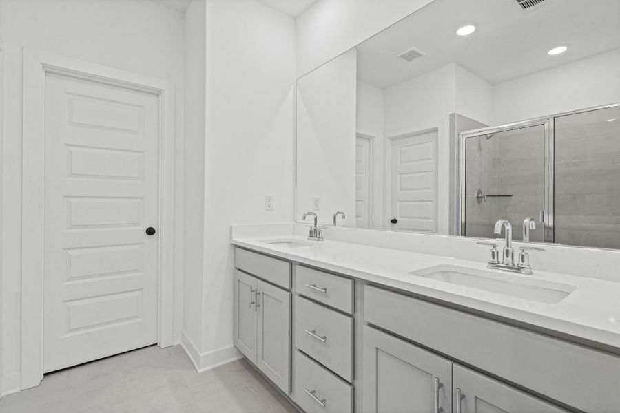 Dual vanity featuring light gray cabinetry, white countertops, chrome fixtures, and undermount sinks