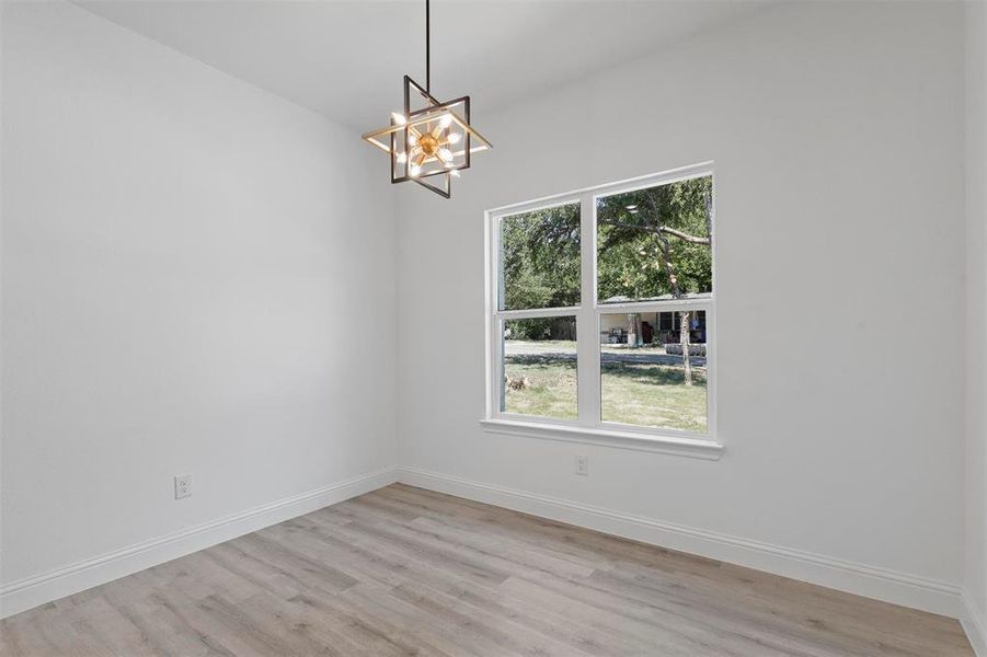 Empty room with light hardwood / wood-style flooring and a chandelier