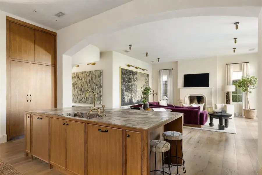 Kitchen with brown cabinets, an island with sink, open floor plan, and a fireplace