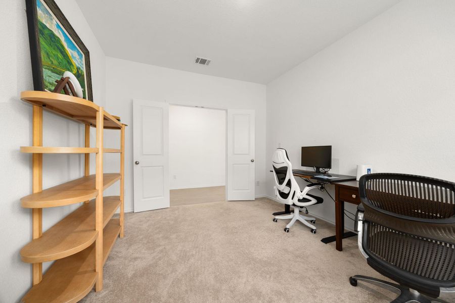 A quiet room featuring soft carpeting and a clear view to an adjacent space through a wide doorway.