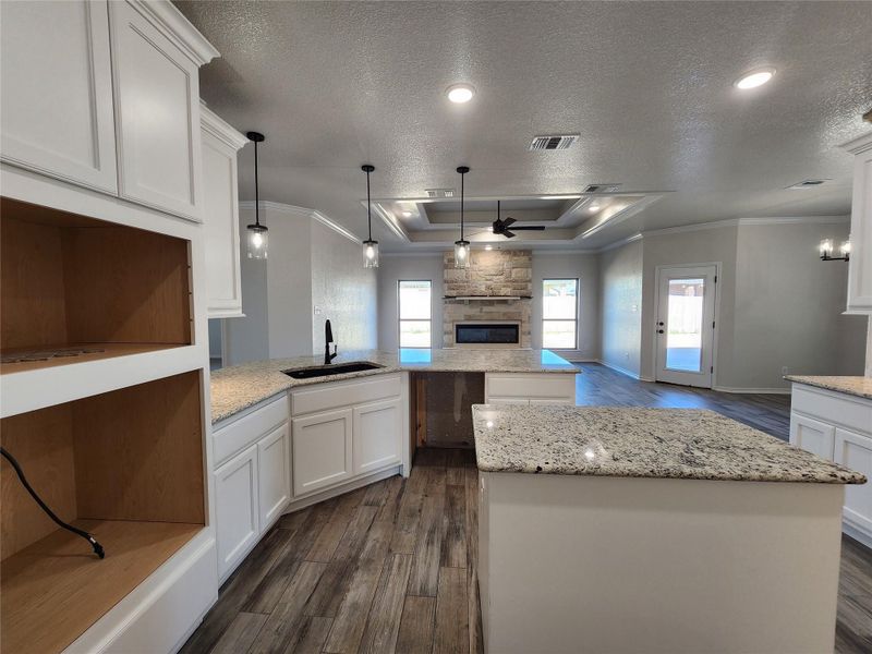 Kitchen featuring a textured ceiling, crown molding, ceiling fan, white cabinets, and pendant lighting