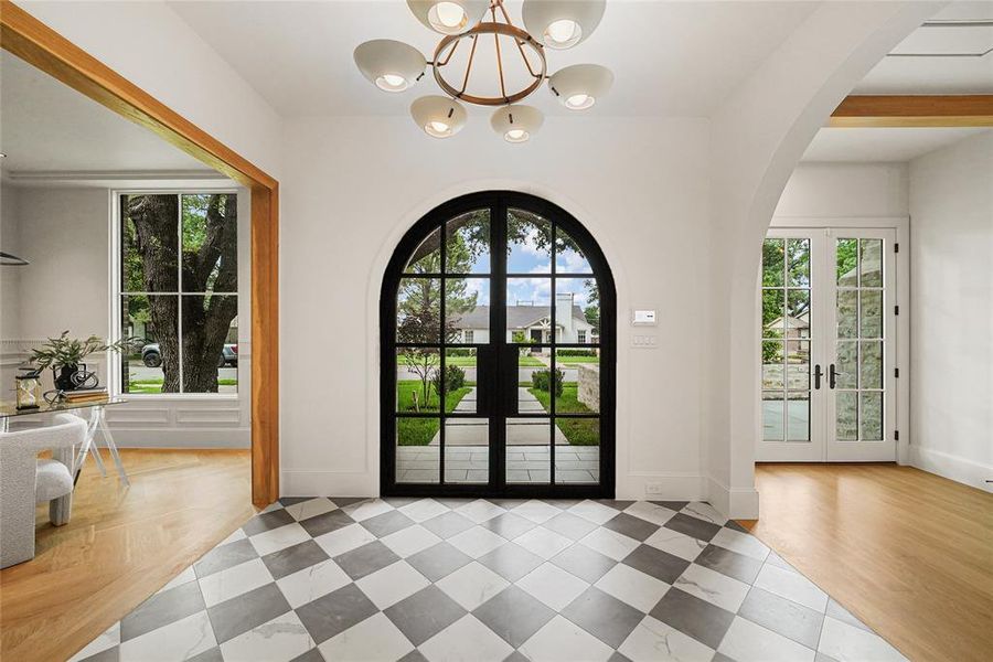 Arched glass-paned double entry doors with a checkered tile floor