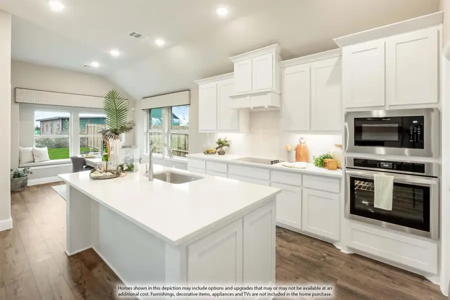 Kitchen with white cabinets, center island with sink, stainless steel appliances, and hardwood floors