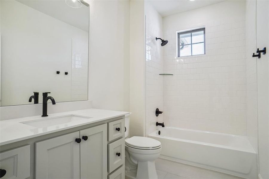 Full bathroom featuring toilet, tile patterned flooring, vanity, and tiled shower / bath