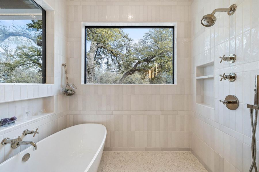 Bathroom with a freestanding tub, a tile shower, and tile walls