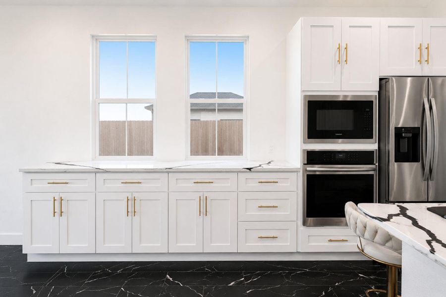 A well-appointed kitchen showcasing contemporary white cabinetry with elegant gold hardware.
