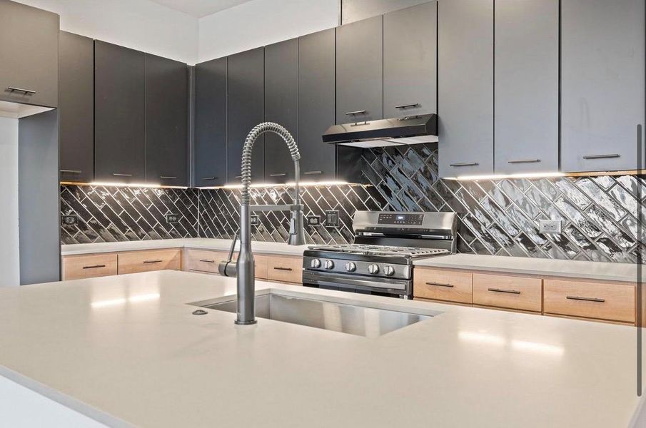 Sleek contemporary cabinetry pairs with a bold herringbone backsplash and solid-surface countertops. Sleek contemporary cabinetry pairs with a bold herringbone backsplash and solid-surface countertops.