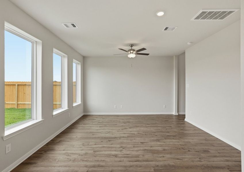 Family room featuring a bank of windows with natural light, a ceiling fan, and wood-look vinyl flooring.