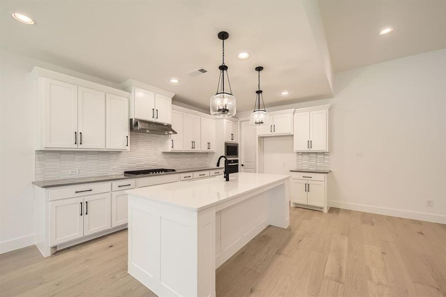 Kitchen featuring appliances with stainless steel finishes, recessed lighting, under cabinet range hood, backsplash, and white cabinets