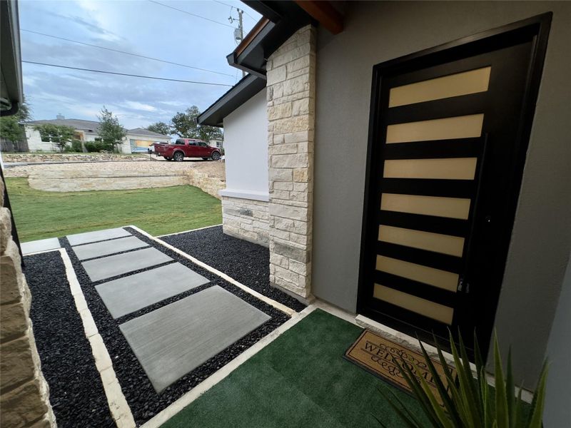Property entrance with stone siding, stucco siding, and a yard Property entrance with stone siding, stucco siding, and a yard
