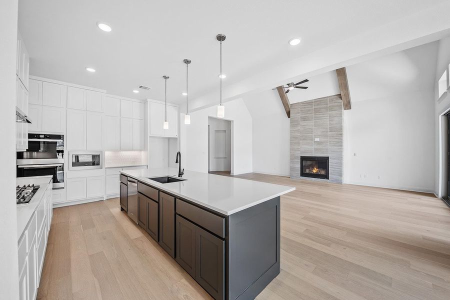 Kitchen with white cabinets, light wood-type flooring, decorative light fixtures, stainless steel appliances, and recessed lighting
